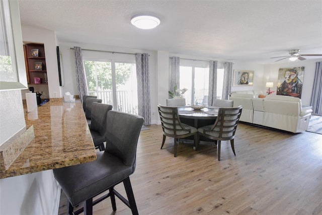 dining space with ceiling fan, light hardwood / wood-style floors, and a textured ceiling