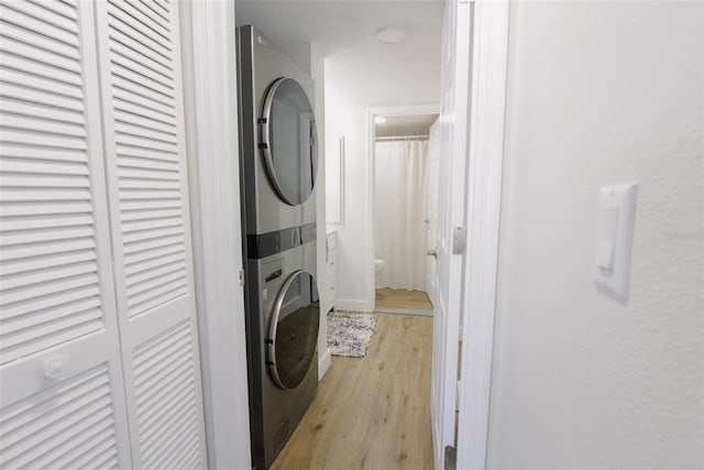 clothes washing area featuring stacked washer and dryer and light hardwood / wood-style floors