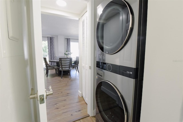 laundry room with light hardwood / wood-style floors and stacked washer / dryer