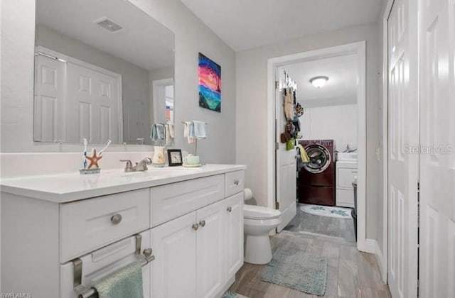 bathroom with vanity, toilet, wood-type flooring, and washing machine and clothes dryer