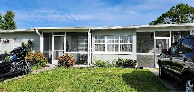 view of front of home with a sunroom and a front lawn