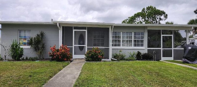 view of front of home with a front yard and a sunroom