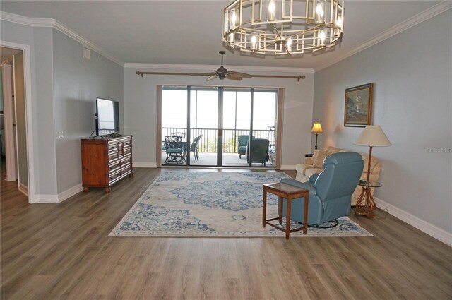 living room with ceiling fan with notable chandelier, dark wood-type flooring, and crown molding