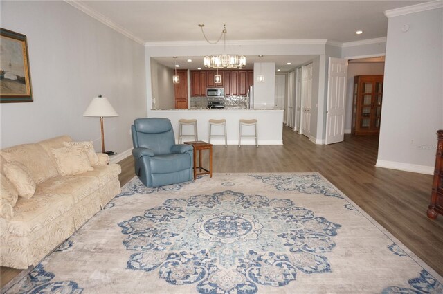 living room featuring an inviting chandelier, dark wood-type flooring, and ornamental molding