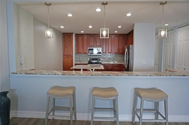 kitchen with decorative backsplash, kitchen peninsula, stainless steel appliances, and hanging light fixtures