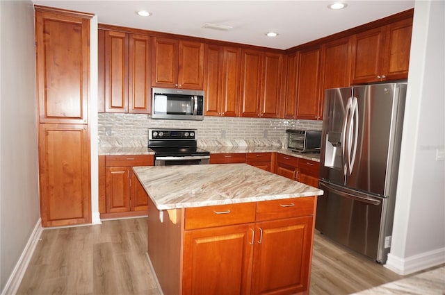 kitchen featuring light wood-type flooring, decorative backsplash, a center island, and stainless steel appliances