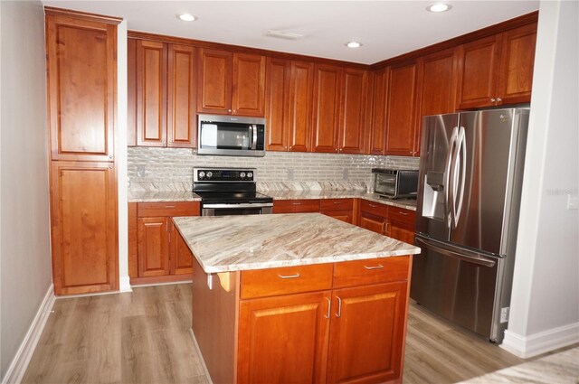 kitchen featuring light wood-type flooring, decorative backsplash, a center island, and stainless steel appliances