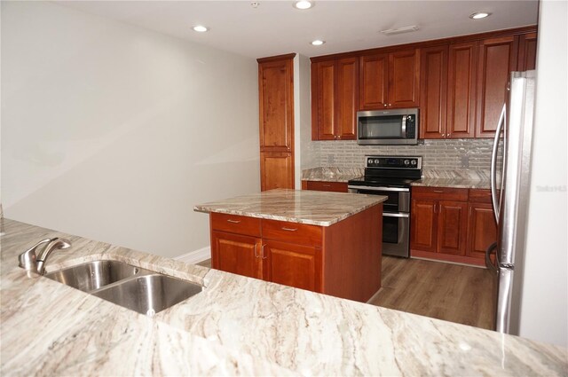 kitchen featuring light stone countertops, appliances with stainless steel finishes, tasteful backsplash, dark wood-type flooring, and sink