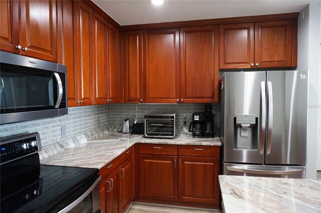 kitchen with light stone countertops, appliances with stainless steel finishes, and backsplash