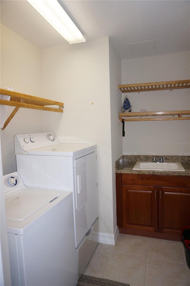 laundry area with washer and clothes dryer, light tile patterned flooring, cabinets, and sink