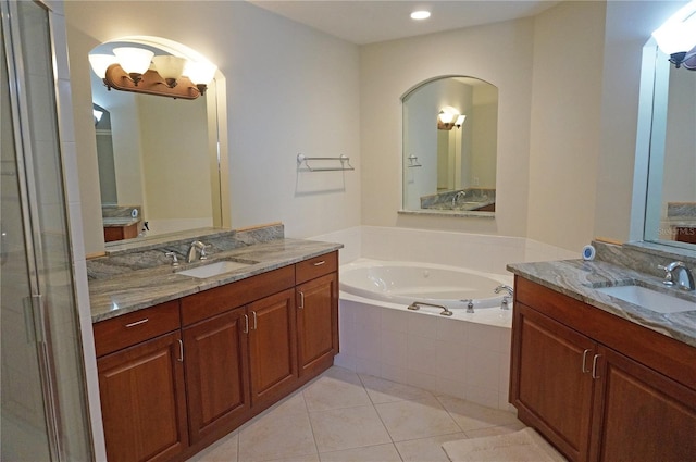 bathroom with tile patterned floors, tiled tub, and vanity