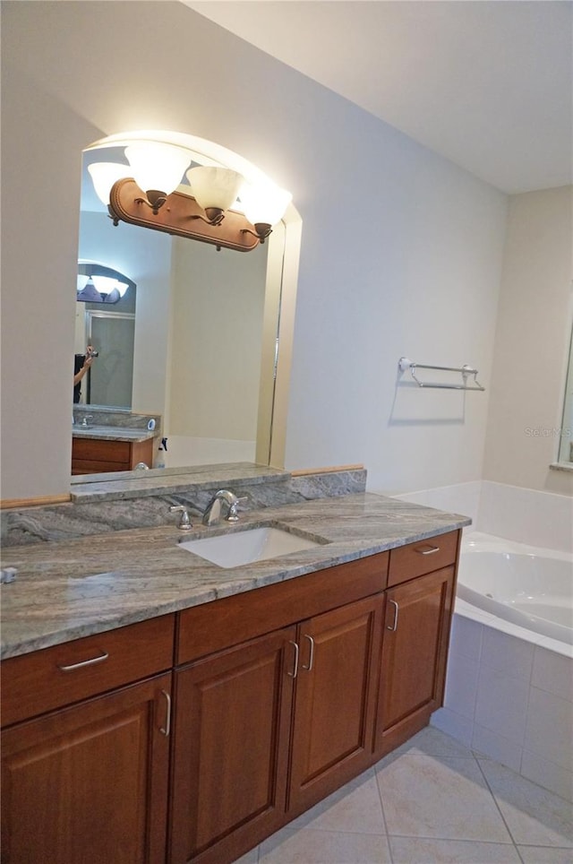 bathroom with vanity, tile patterned floors, and tiled tub