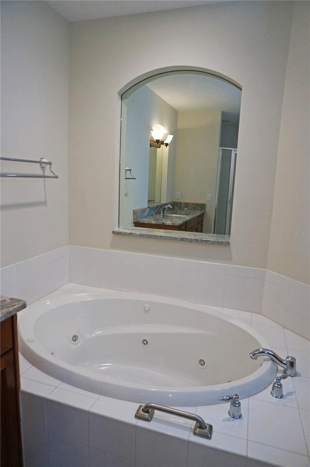 bathroom with tiled tub and vanity