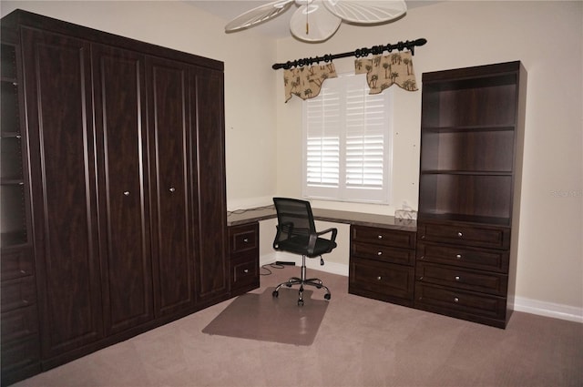 carpeted office space featuring ceiling fan and built in desk