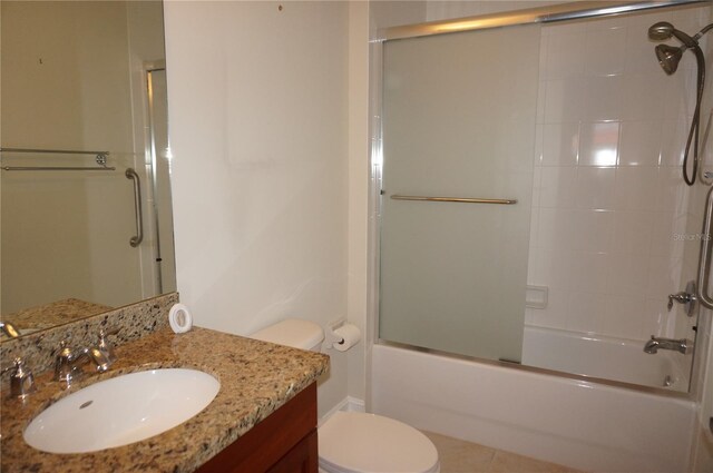 full bathroom with combined bath / shower with glass door, vanity, toilet, and tile patterned flooring