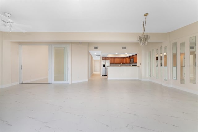 unfurnished living room featuring ceiling fan with notable chandelier