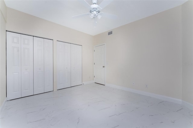 unfurnished bedroom with ceiling fan and two closets