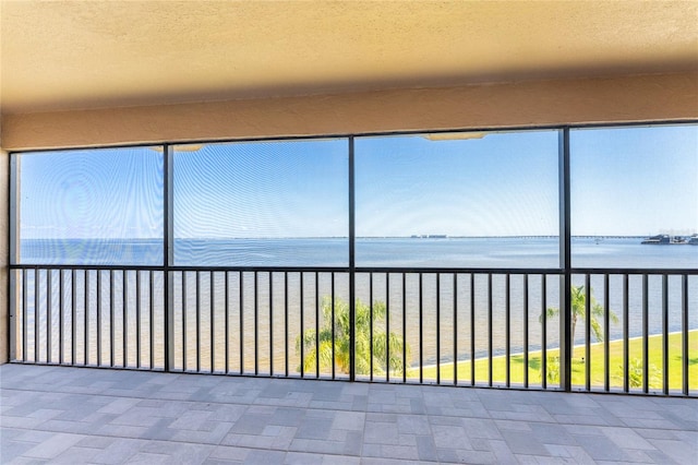 unfurnished sunroom with a water view and a beach view