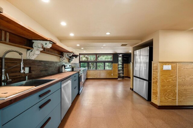 kitchen with open shelves, stainless steel appliances, butcher block counters, visible vents, and a sink