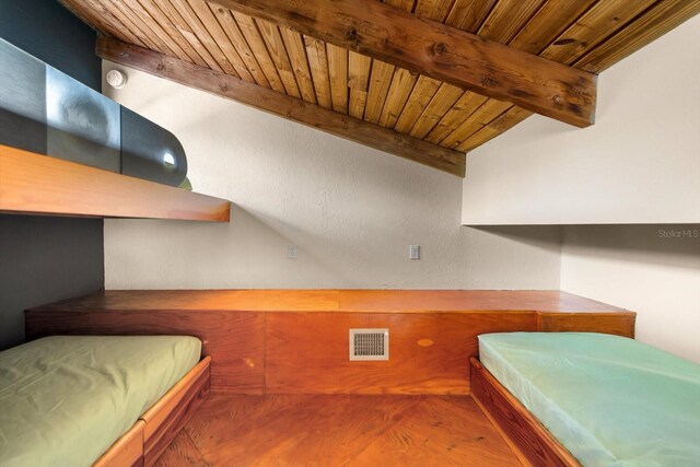 bedroom with visible vents, wooden ceiling, wood finished floors, and beam ceiling