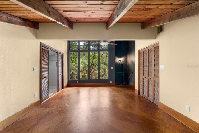 empty room featuring baseboards, wood ceiling, visible vents, and beamed ceiling