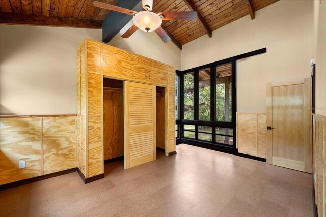 unfurnished bedroom featuring high vaulted ceiling, a wainscoted wall, wood ceiling, tile patterned floors, and beamed ceiling