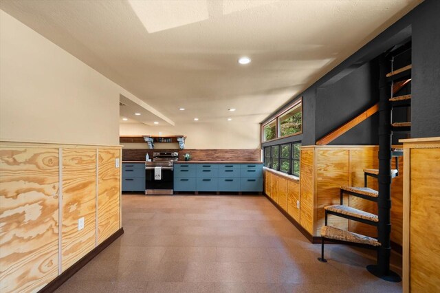 interior space with recessed lighting, a wainscoted wall, stainless steel electric range oven, and light floors