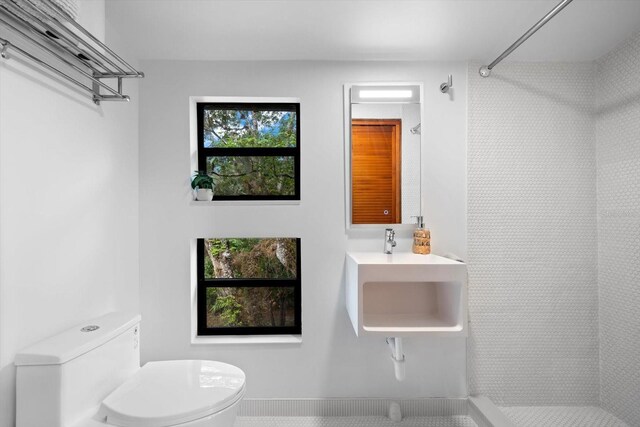 full bath with toilet, a sink, and tiled shower