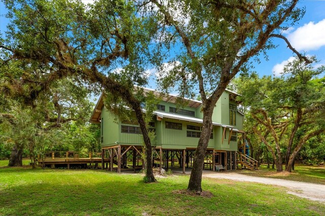 back of property with driveway, stairs, a carport, and a yard