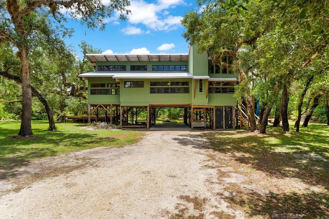 view of front of property with dirt driveway, stairway, a front lawn, and a carport