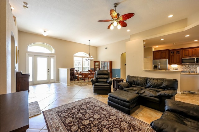 living room with light tile patterned floors, ceiling fan with notable chandelier, and a textured ceiling