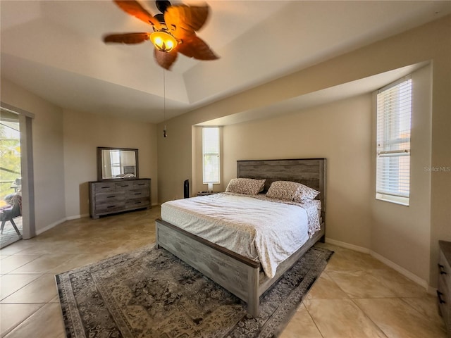 bedroom featuring access to exterior, a raised ceiling, ceiling fan, and light tile patterned flooring