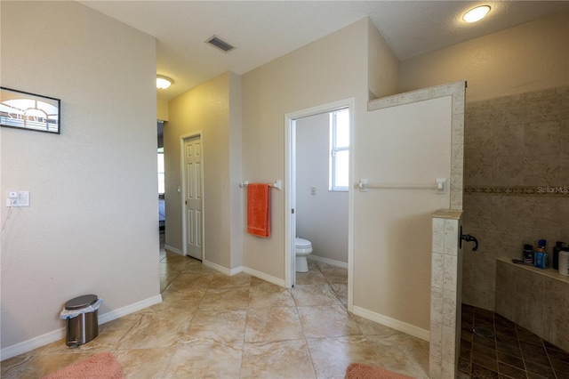 bathroom featuring toilet and a tile shower