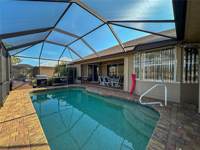 view of pool with a patio, glass enclosure, and grilling area