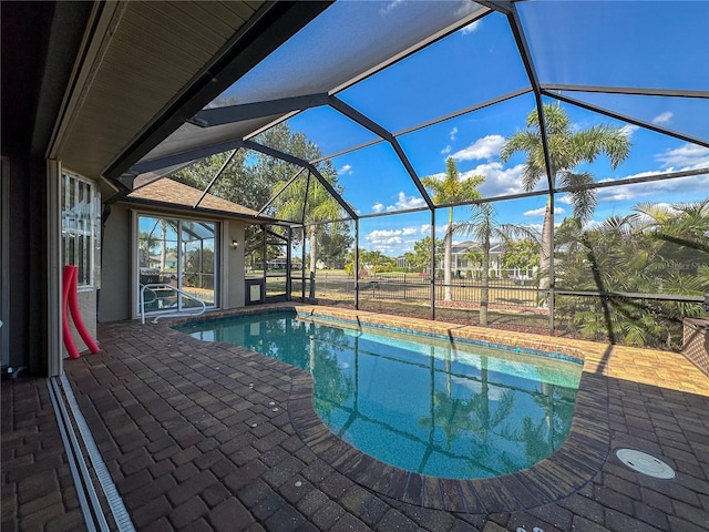 view of swimming pool featuring glass enclosure and a patio area