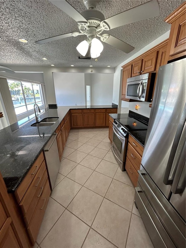 kitchen with sink, ceiling fan, light tile patterned flooring, kitchen peninsula, and stainless steel appliances