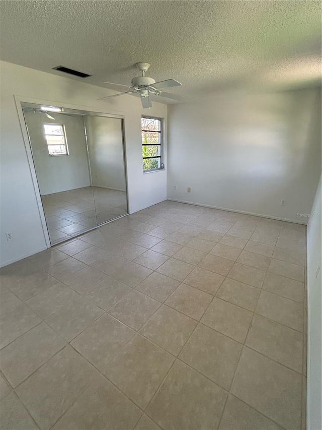 unfurnished room with ceiling fan, light tile patterned flooring, and a textured ceiling