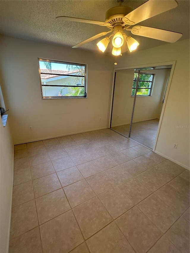 unfurnished bedroom featuring ceiling fan, a closet, and light tile patterned floors