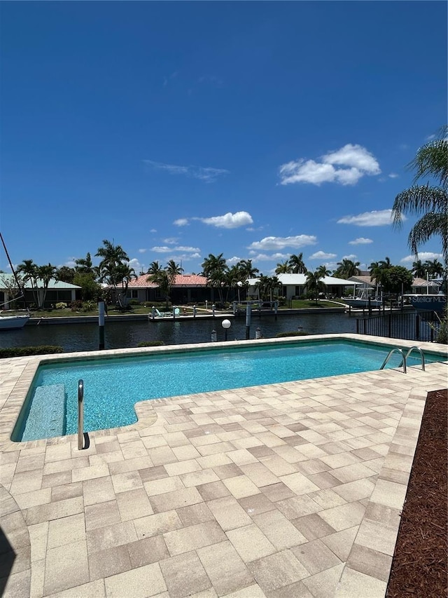 view of pool with a water view and a patio