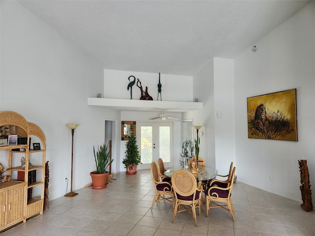 tiled dining area featuring ceiling fan, french doors, a towering ceiling, and a textured ceiling