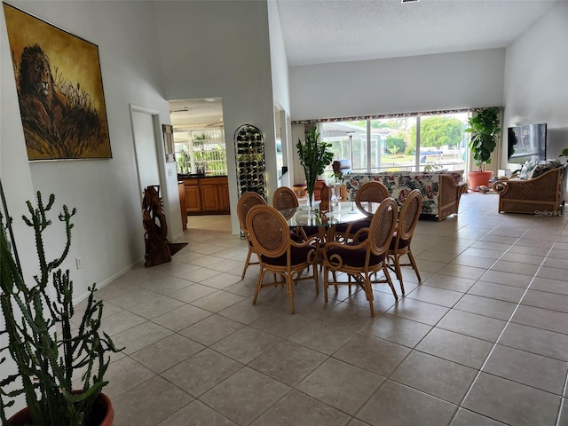 tiled dining area featuring a textured ceiling and a towering ceiling