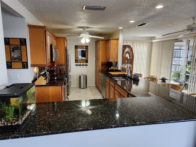 kitchen featuring dark stone counters, kitchen peninsula, and stainless steel appliances