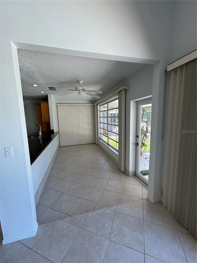 hall featuring light tile patterned floors and a textured ceiling