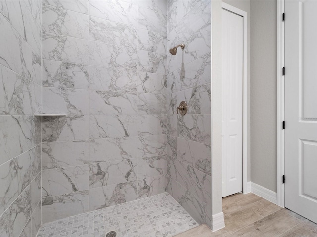 bathroom with hardwood / wood-style flooring and a tile shower