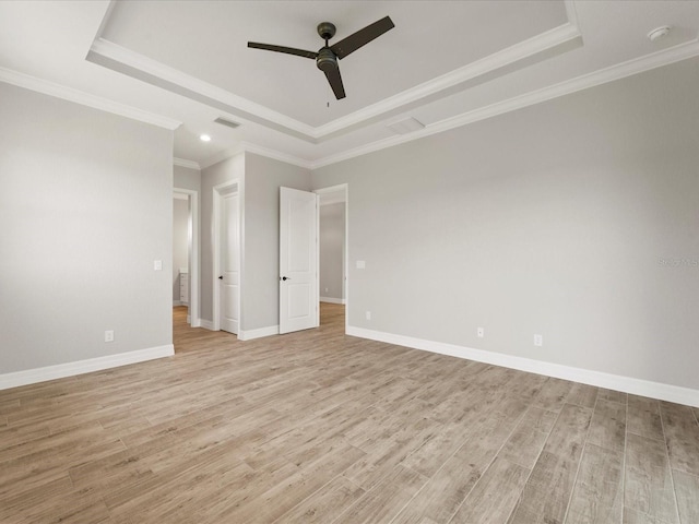 unfurnished room with ornamental molding, light wood-type flooring, a tray ceiling, and ceiling fan