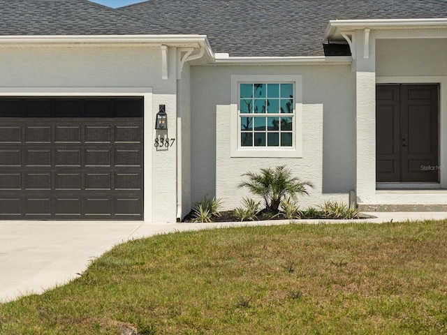 view of exterior entry featuring a garage and a yard