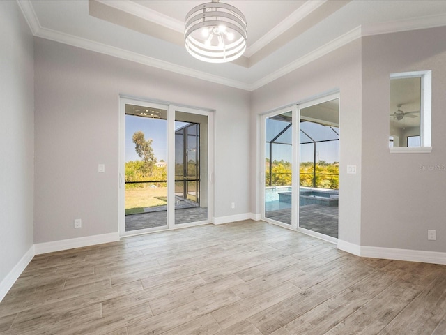 spare room with a wealth of natural light, a tray ceiling, light hardwood / wood-style floors, and ornamental molding