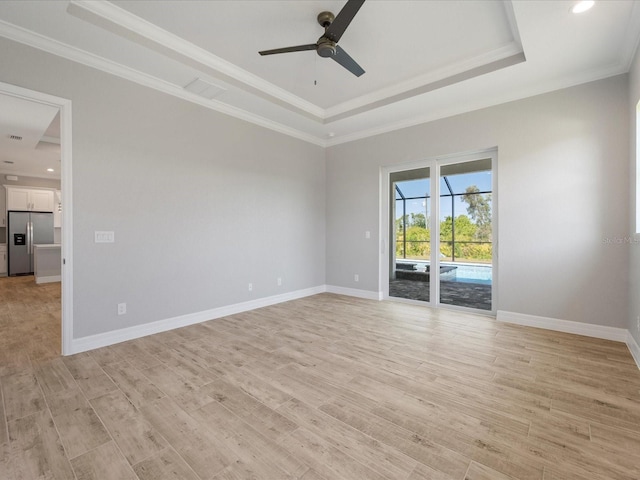 spare room with light hardwood / wood-style floors, ceiling fan, a raised ceiling, and crown molding