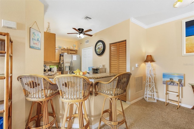 dining space featuring light carpet, ornamental molding, and ceiling fan