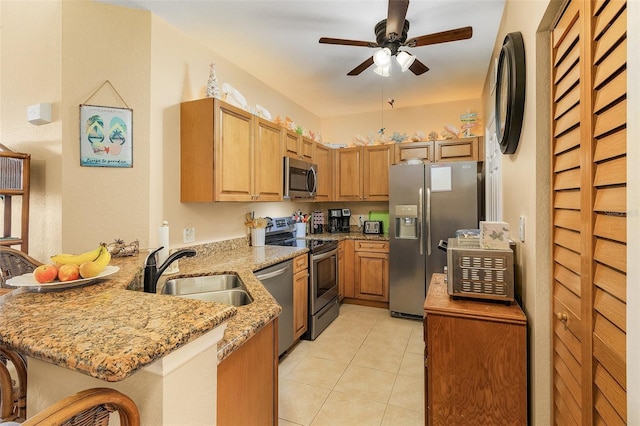 kitchen with sink, a kitchen breakfast bar, kitchen peninsula, stainless steel appliances, and light stone countertops